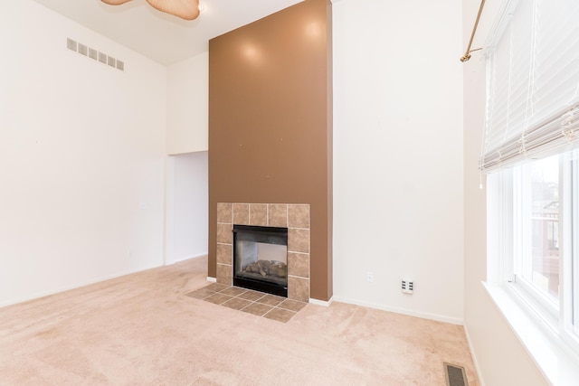 unfurnished living room with visible vents, plenty of natural light, carpet flooring, and a fireplace