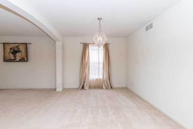 spare room featuring light carpet, visible vents, a chandelier, and ornate columns