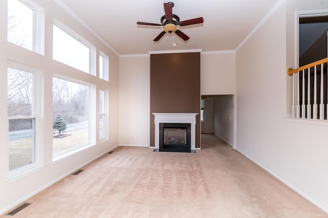 unfurnished living room featuring visible vents, a fireplace with flush hearth, light carpet, and ornamental molding