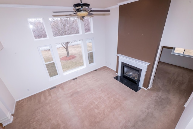 unfurnished living room featuring a fireplace with flush hearth, carpet floors, visible vents, and crown molding