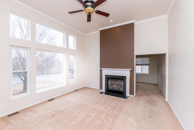 unfurnished living room with carpet, baseboards, visible vents, a fireplace with flush hearth, and ornamental molding