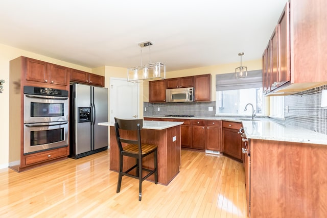 kitchen with a kitchen island, a breakfast bar area, decorative backsplash, light wood-style flooring, and stainless steel appliances