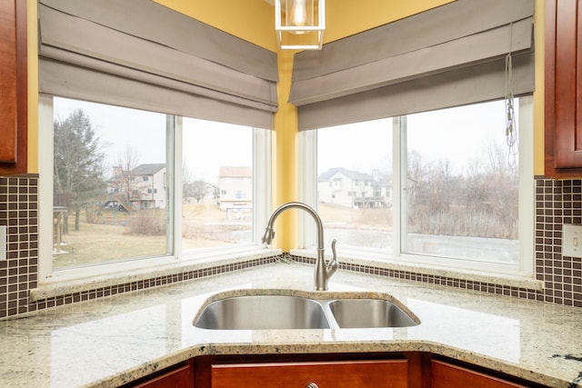 interior space featuring tasteful backsplash, light stone countertops, and a sink