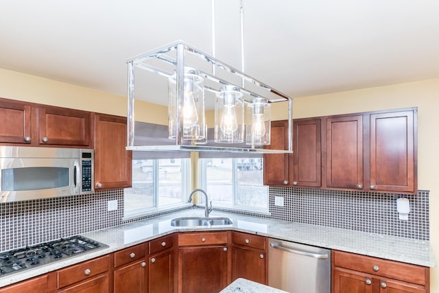 kitchen with tasteful backsplash, appliances with stainless steel finishes, light stone counters, and a sink