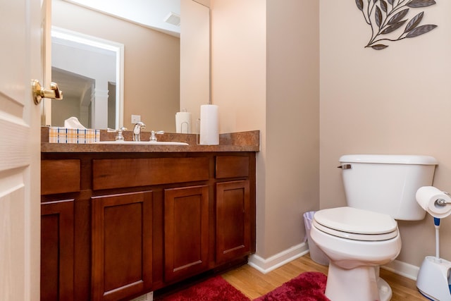 bathroom featuring toilet, wood finished floors, visible vents, and baseboards