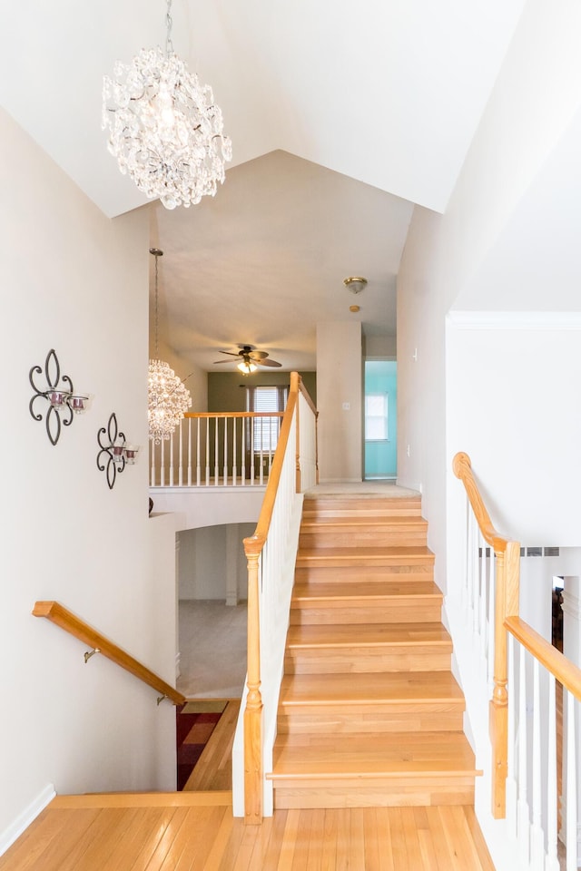 stairs with wood-type flooring and ceiling fan with notable chandelier