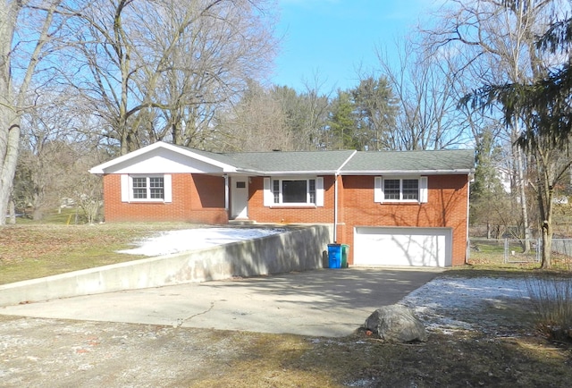 view of front of home featuring brick siding, driveway, an attached garage, and fence