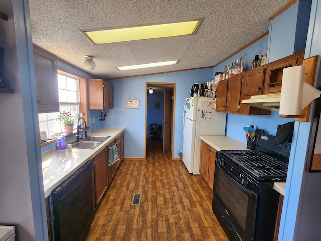 kitchen with visible vents, black appliances, a sink, dark wood-style floors, and light countertops