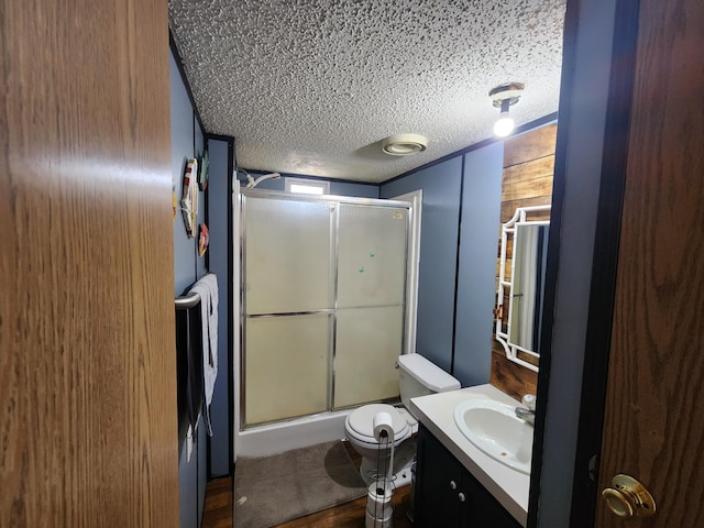 full bathroom featuring a shower with door, a textured ceiling, vanity, and toilet