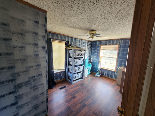 unfurnished bedroom with visible vents, a textured ceiling, wood finished floors, baseboards, and ceiling fan
