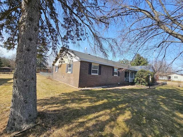 view of home's exterior with a yard, fence, and brick siding