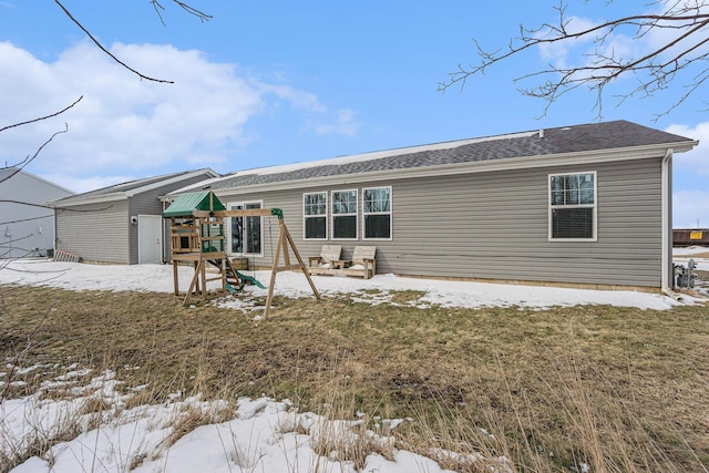 view of front of home featuring an outbuilding, a playground, and roof with shingles