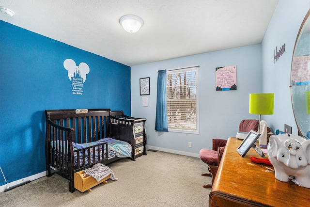 carpeted bedroom with a crib and baseboards