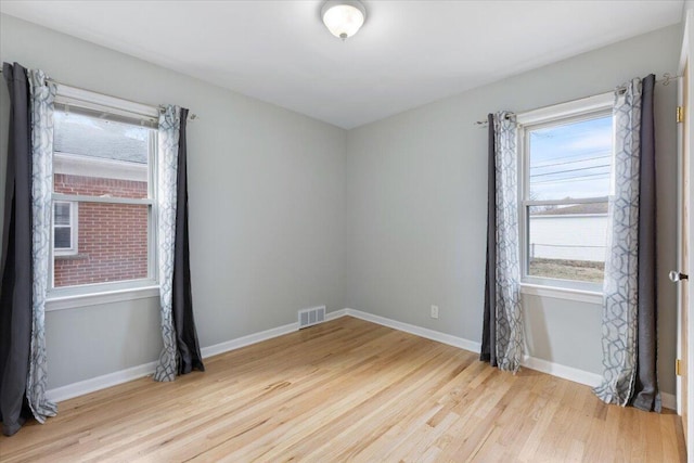 empty room with visible vents, plenty of natural light, light wood-style floors, and baseboards