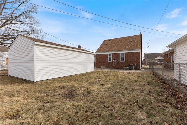 back of property featuring a lawn, fence, an outdoor structure, brick siding, and a patio area