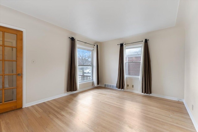 unfurnished room with visible vents, light wood-type flooring, and baseboards