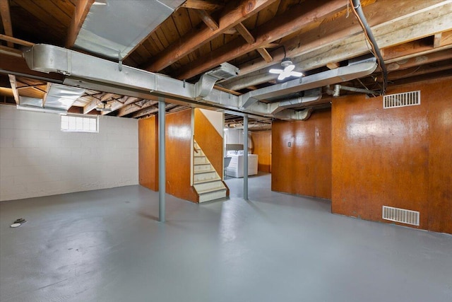 below grade area with visible vents, separate washer and dryer, concrete block wall, and stairs