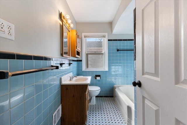 full bathroom featuring visible vents, toilet, a bathing tub, tile walls, and vanity