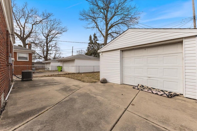 detached garage featuring central AC unit, concrete driveway, and fence