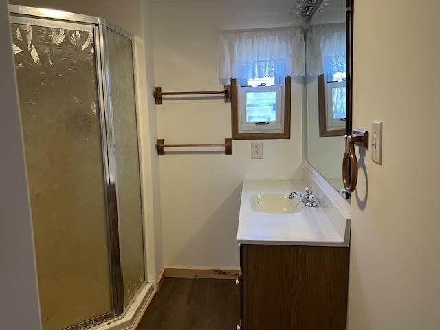 bathroom with baseboards, wood finished floors, a stall shower, and vanity