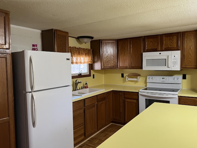 kitchen with a textured ceiling, white appliances, light countertops, and a sink