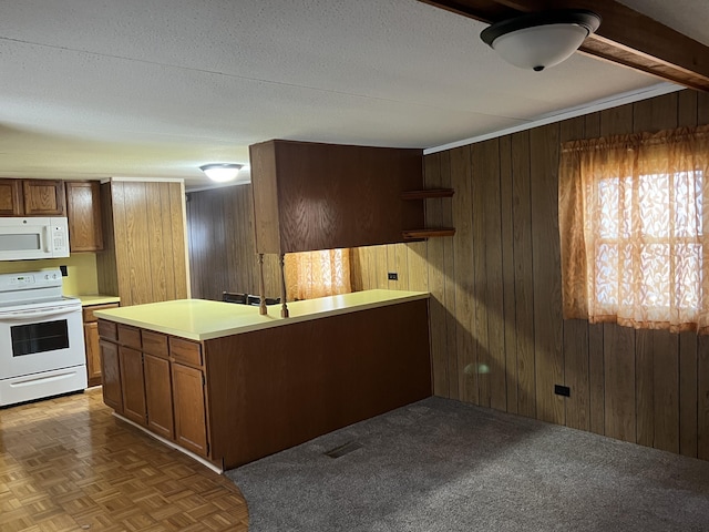 kitchen featuring wooden walls, white appliances, light countertops, and visible vents