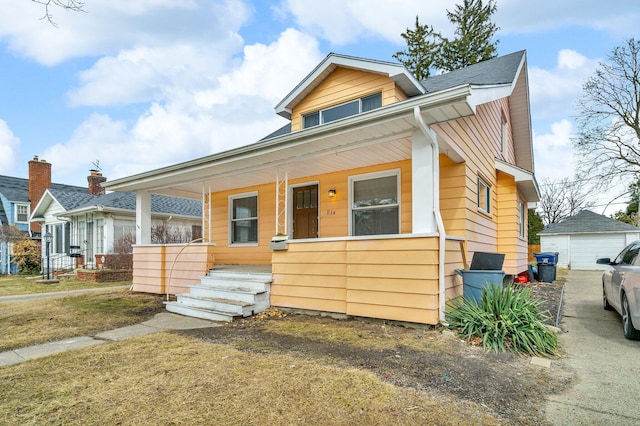 bungalow-style home featuring a garage, an outbuilding, and a porch