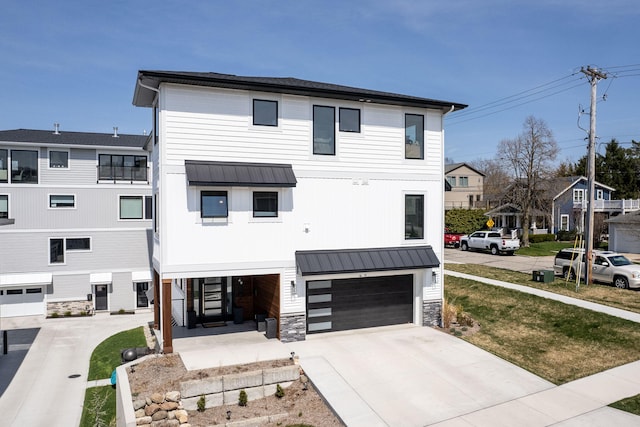 view of front facade with a garage, concrete driveway, metal roof, and a standing seam roof