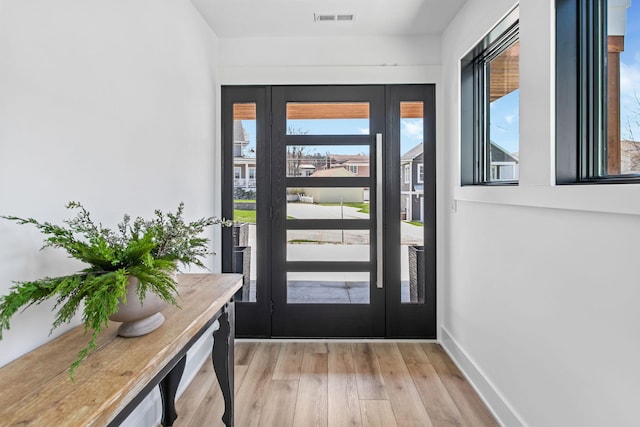 foyer entrance featuring visible vents, baseboards, and light wood-style flooring