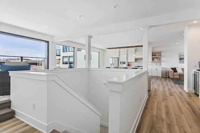 kitchen featuring open floor plan, white cabinets, light wood-style floors, and stainless steel fridge with ice dispenser