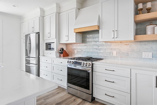 kitchen featuring custom exhaust hood, open shelves, stainless steel appliances, light countertops, and white cabinetry