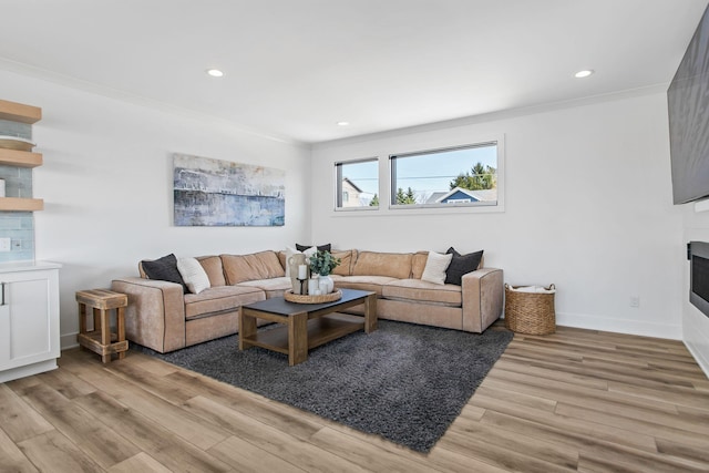 living room with baseboards, recessed lighting, ornamental molding, light wood-type flooring, and a large fireplace