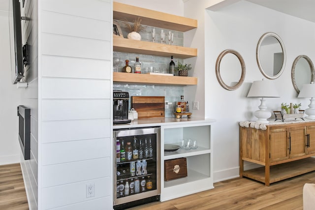 bar featuring baseboards, wood finished floors, beverage cooler, and a dry bar