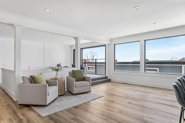 interior space featuring light wood-style flooring, recessed lighting, a healthy amount of sunlight, and ornate columns