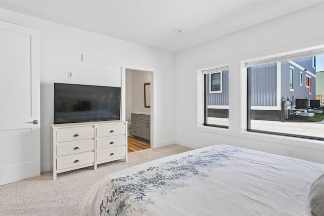 bedroom featuring baseboards, light carpet, and ensuite bath