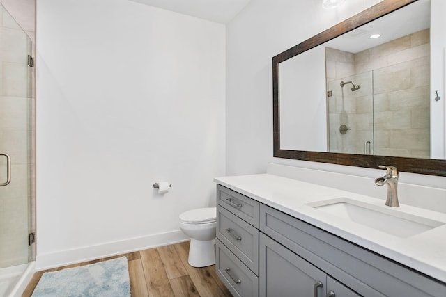 bathroom with a shower stall, vanity, baseboards, and wood finished floors