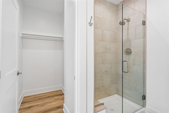 bathroom with wood finished floors, a stall shower, and baseboards