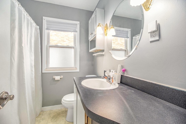 bathroom with toilet, vanity, and baseboards