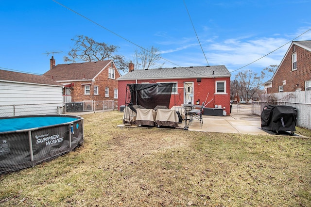 rear view of property featuring a patio, a fenced backyard, brick siding, and a lawn