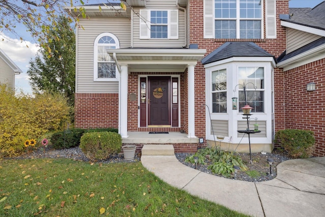 doorway to property with brick siding and a lawn