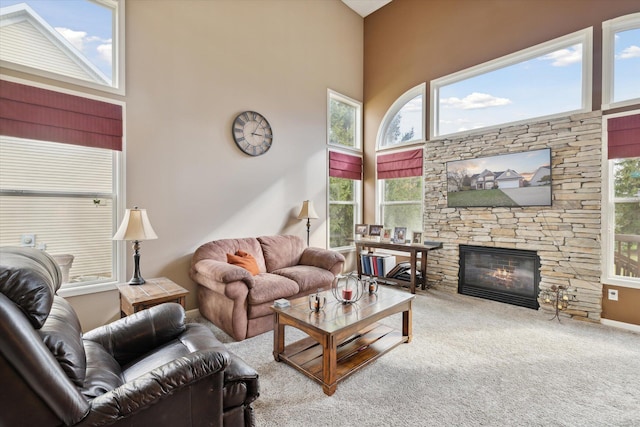 living area with carpet, a towering ceiling, and a fireplace