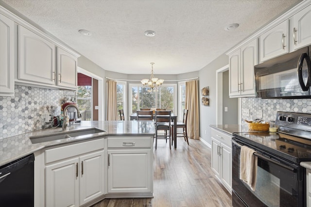 kitchen featuring black appliances, white cabinets, a peninsula, and a sink