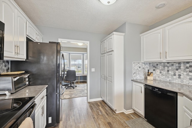 kitchen featuring light wood finished floors, tasteful backsplash, dishwasher, and white cabinetry