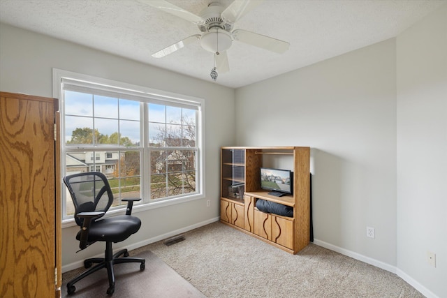 carpeted office space featuring visible vents, a textured ceiling, a ceiling fan, and baseboards