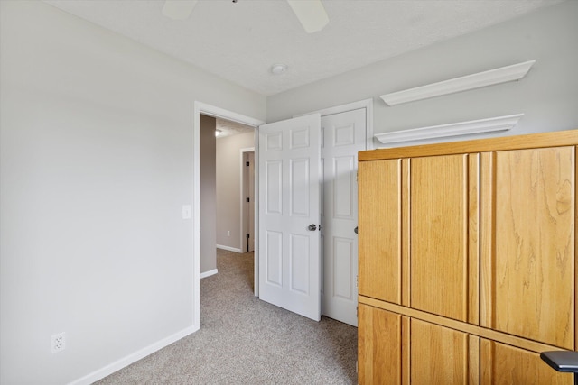 unfurnished bedroom with light carpet, a ceiling fan, and baseboards