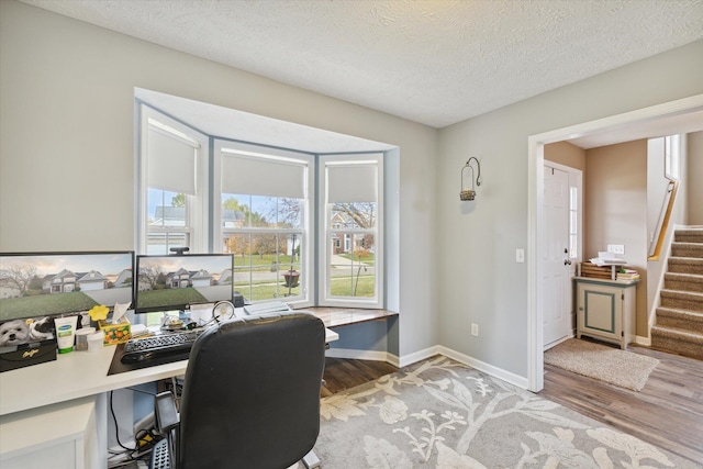 office area featuring a textured ceiling, light wood-type flooring, and baseboards