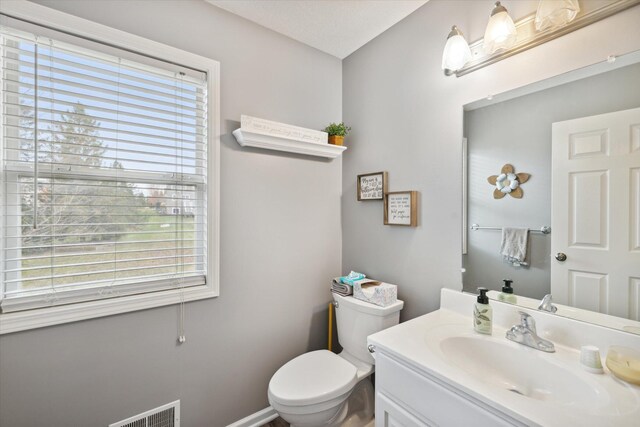 bathroom featuring vanity, toilet, and visible vents