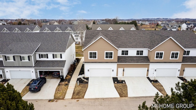 view of front facade featuring a residential view, driveway, a shingled roof, and an attached garage