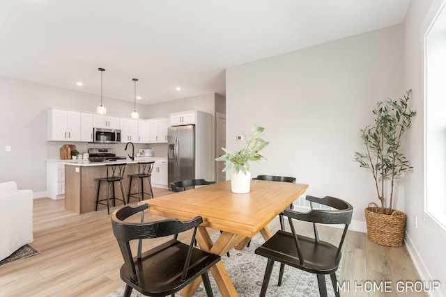 dining space with light wood finished floors, recessed lighting, and baseboards