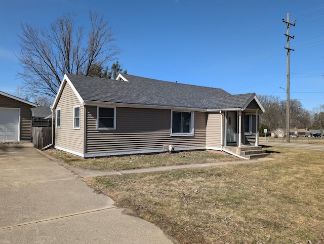 view of front of property featuring an outbuilding, a front lawn, and a shingled roof